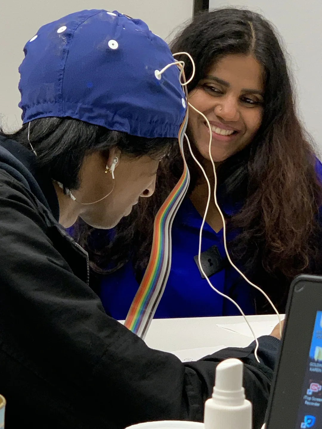 Kohila Sivas beside a participant wearing an EEG cap