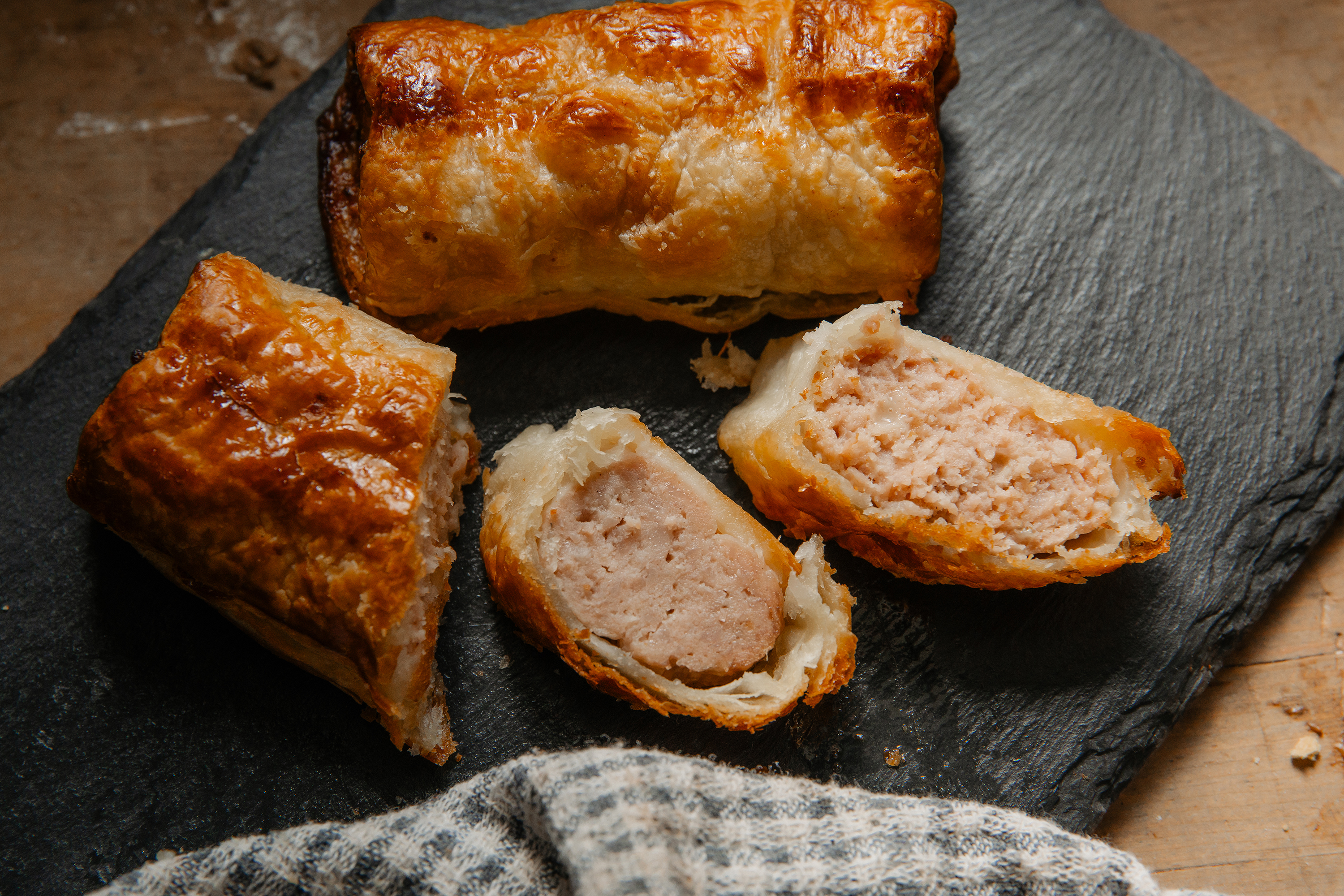 Sausage rolls on a slate board one cut in half Sausage rolls on a slate board one cut in half