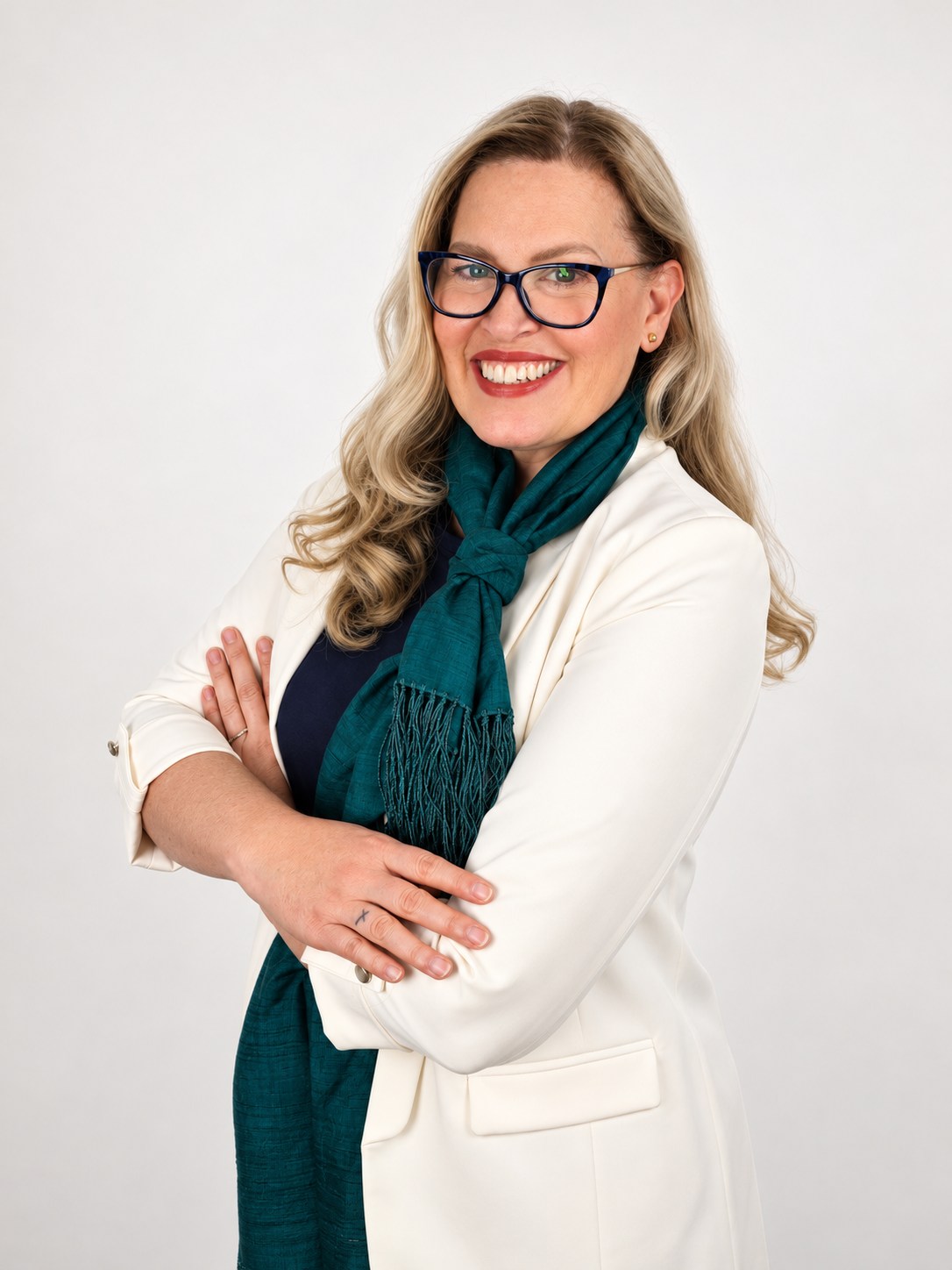 Mayra Sanchez in a white blazer, glasses and teal scarf, smiling