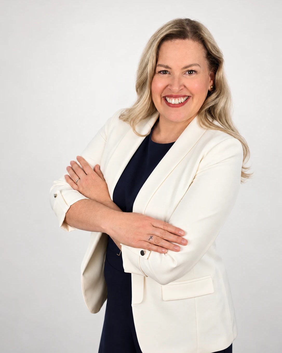 Mayra Sanchez smiling in a white blazer, arms crossed