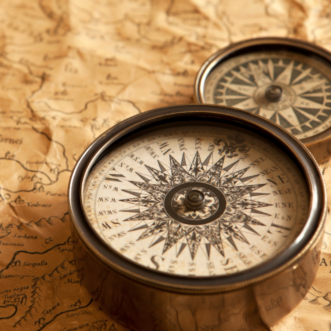 Close-up of an antique compass on an old world map, symbolizing navigation or direction.