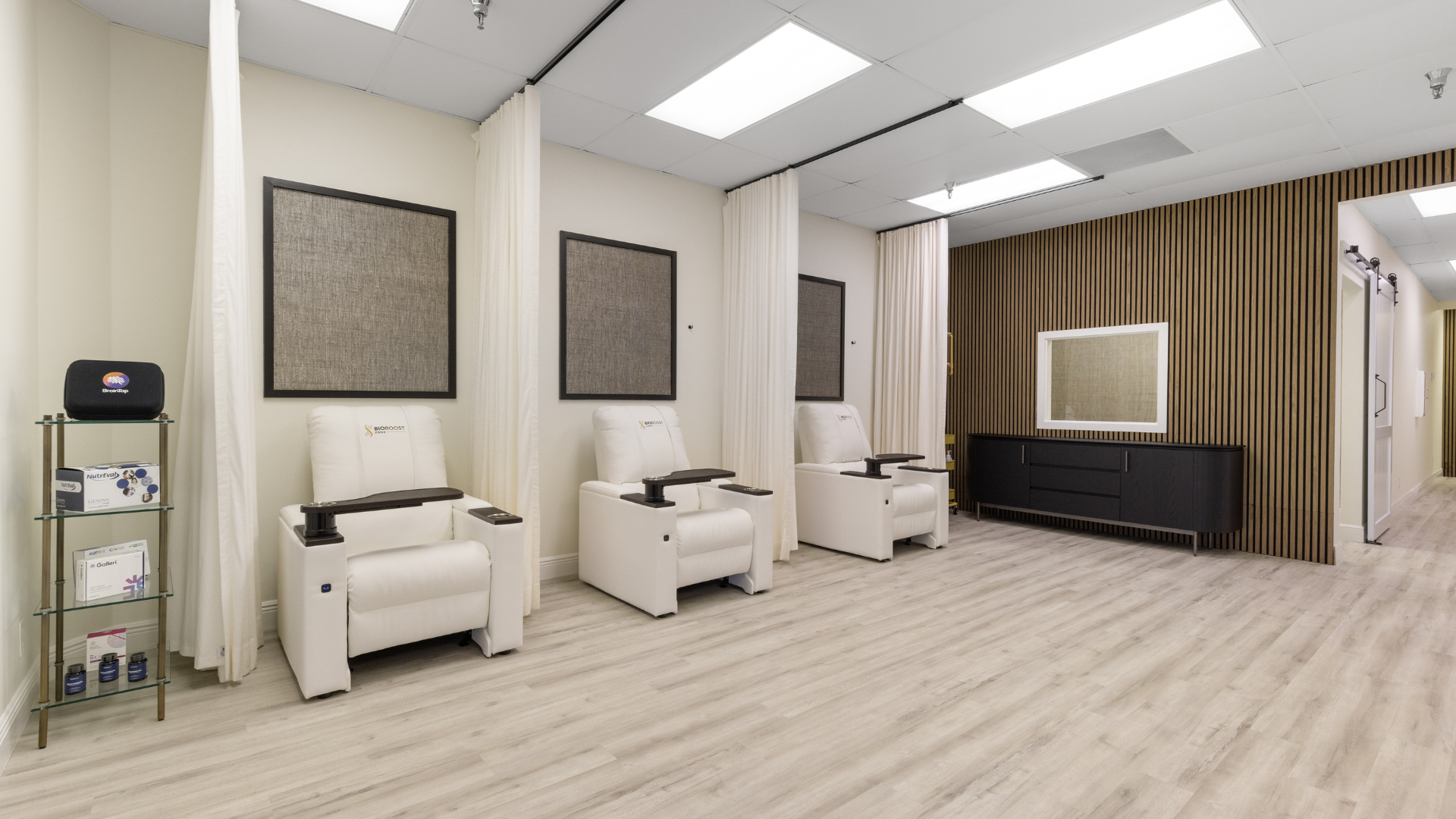 A modern wellness clinic with white recliner chairs and private curtain dividers for IV therapy sessions.