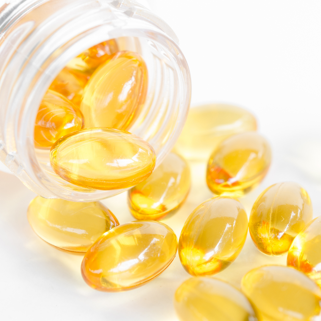 Yellow softgel capsules spilling from a clear bottle onto a white background.