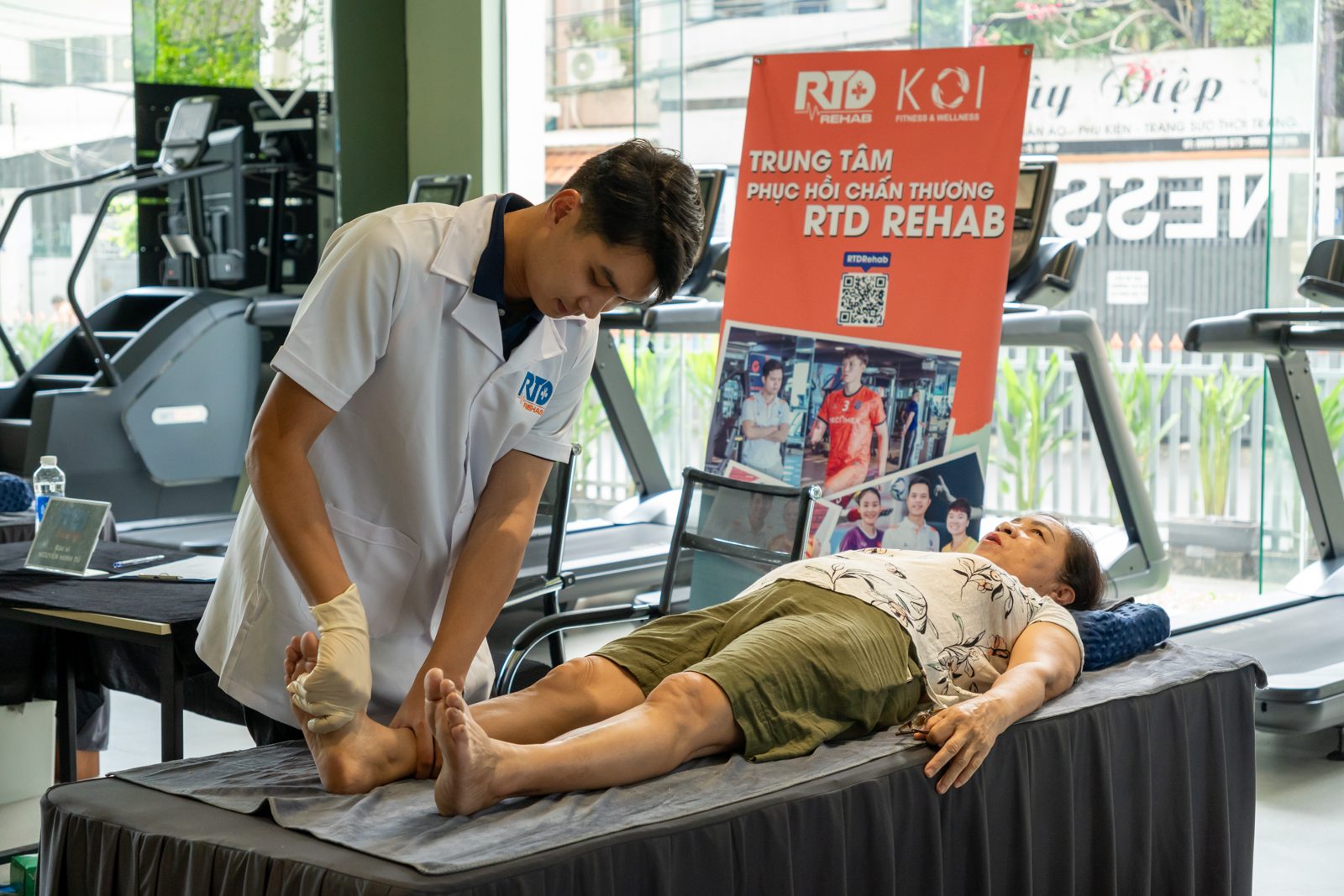 Bác sĩ kiểm tra gối cho người bệnh nằm trên giường tập