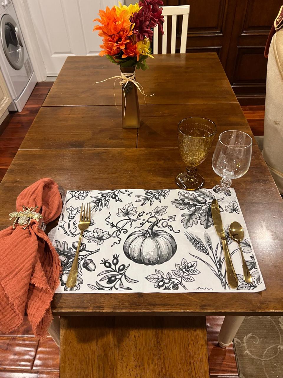 Hand placing a neutral paper placemat at a Thanksgiving place setting Hand placing a neutral paper placemat at a Thanksgiving place setting