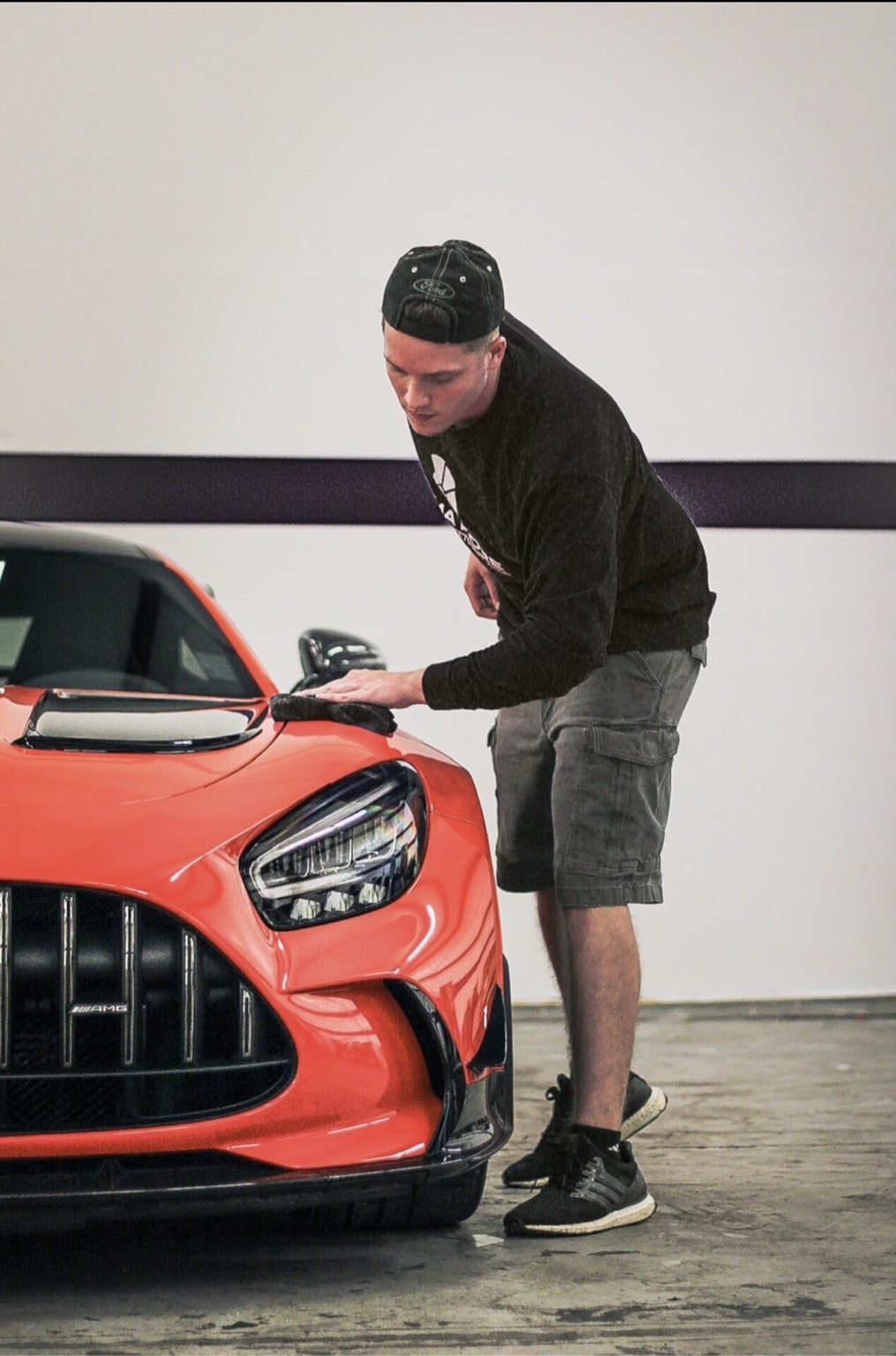 Connor carefully detailing an orange performance car at work