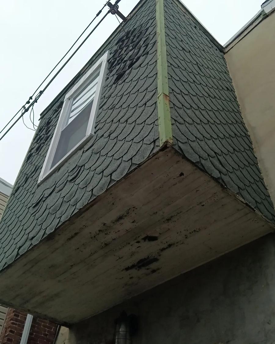 Failing shingle siding on a dormer overhang, seen from the street