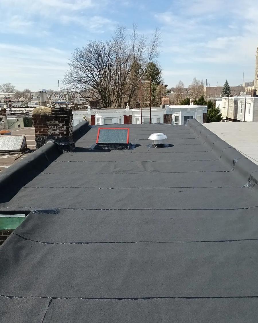 The finished roof, clean to the parapet, church steeple beyond