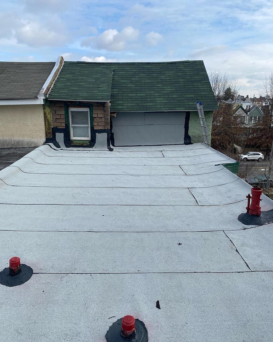 The same roof finished and coated white, garage and dormer beyond