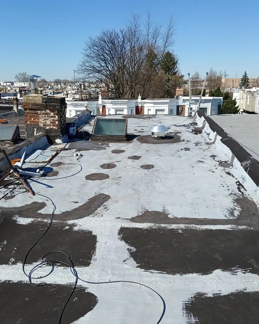 Old roof stripped back, hoses and debris across it, mid tear-off