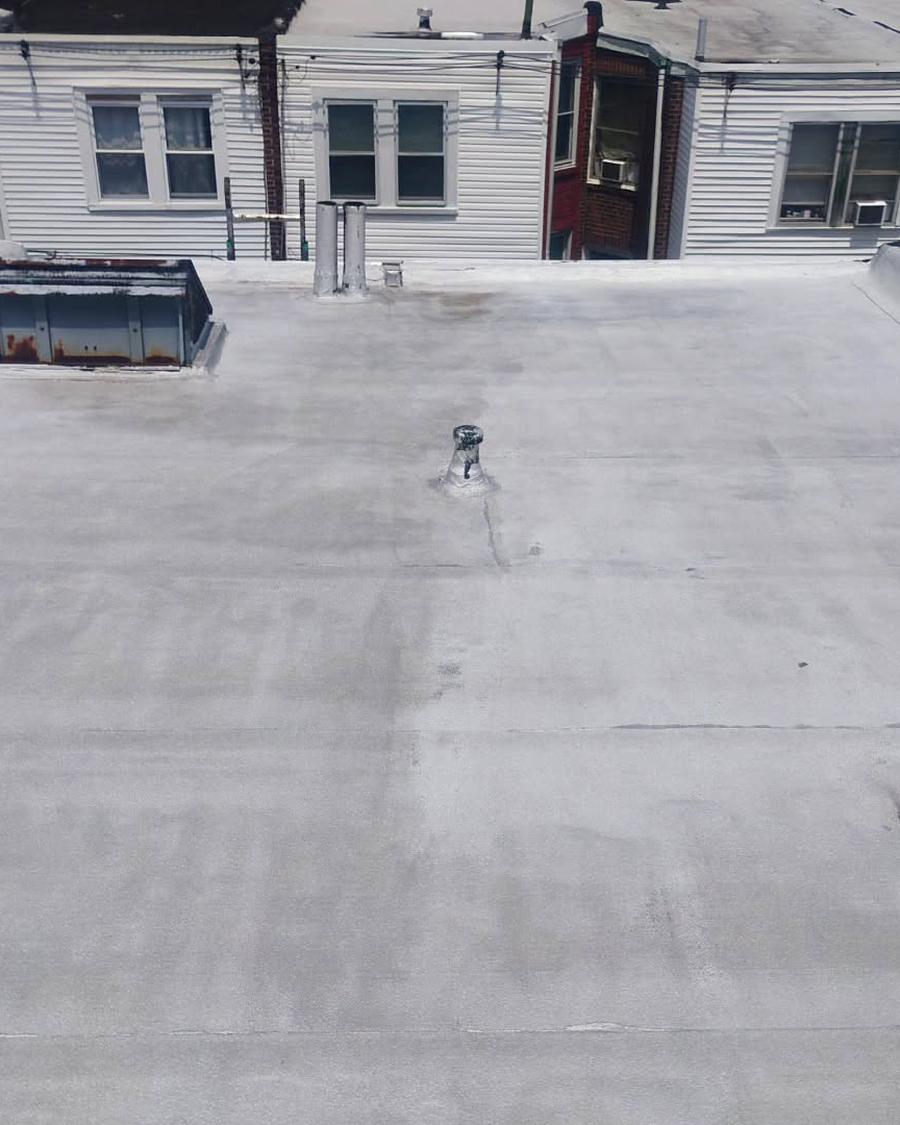 Worn roof coating along a run of white-sided row homes