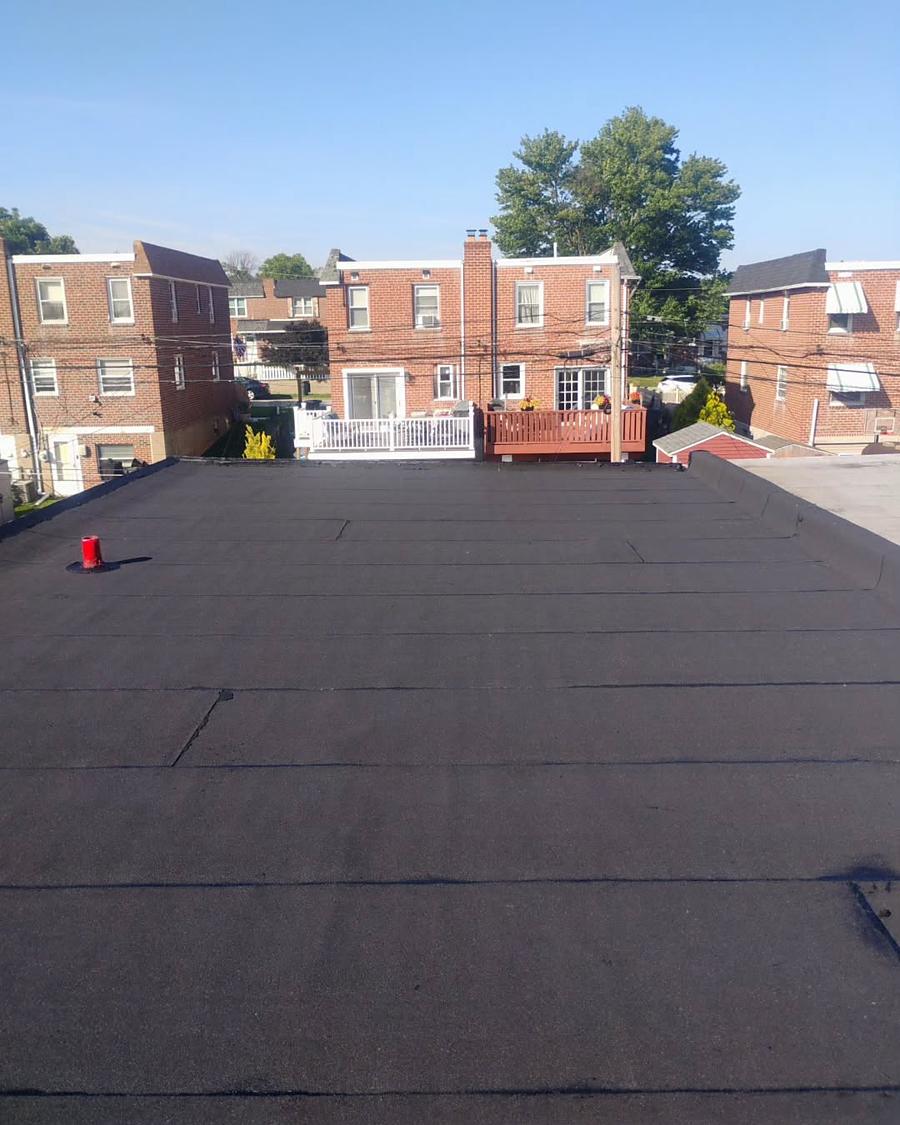 The same roof relaid in new granulated cap sheet, a fresh red pipe boot set in it