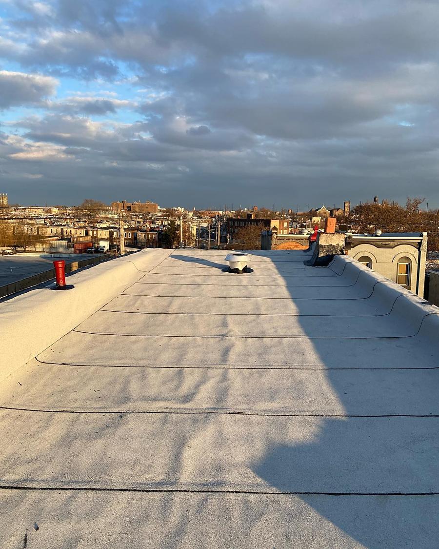 The finished roof, smooth from parapet to parapet, city behind it