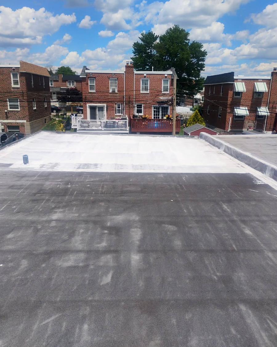Failed white roof coating breaking up across a Philadelphia row home flat roof