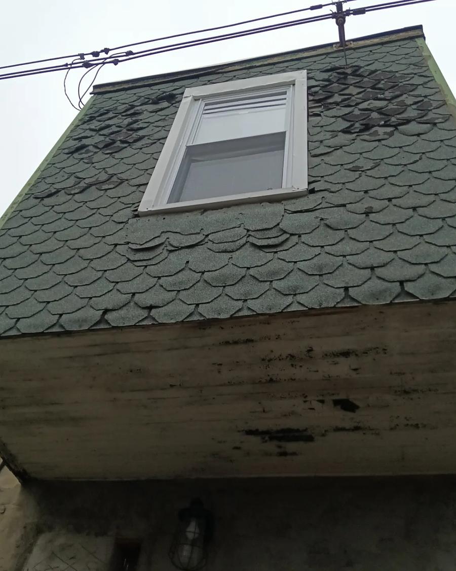 Old green scalloped shingle siding and a stained soffit on a Philadelphia dormer