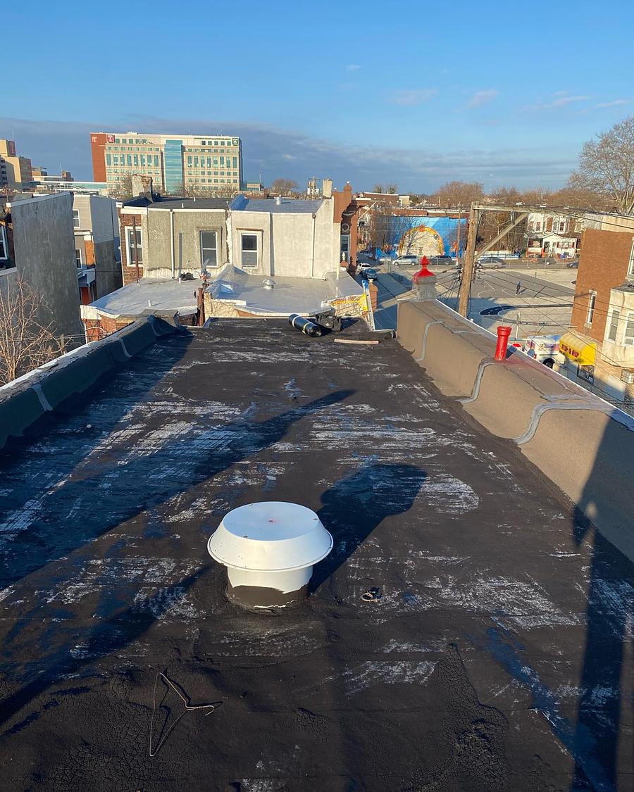 Torn, blistered flat roof with old patch work before replacement