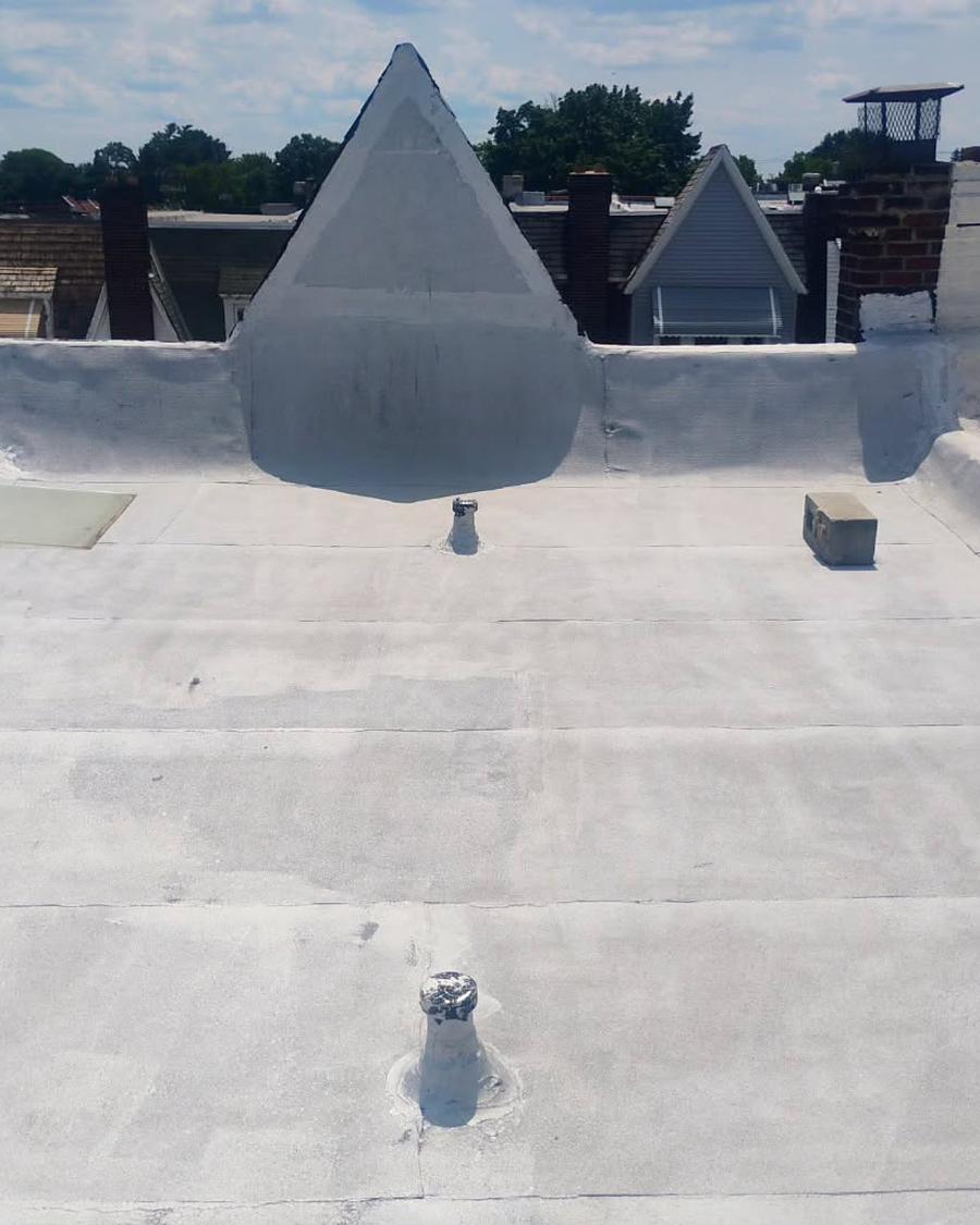 Aged grey roof coating breaking down around a cone dormer