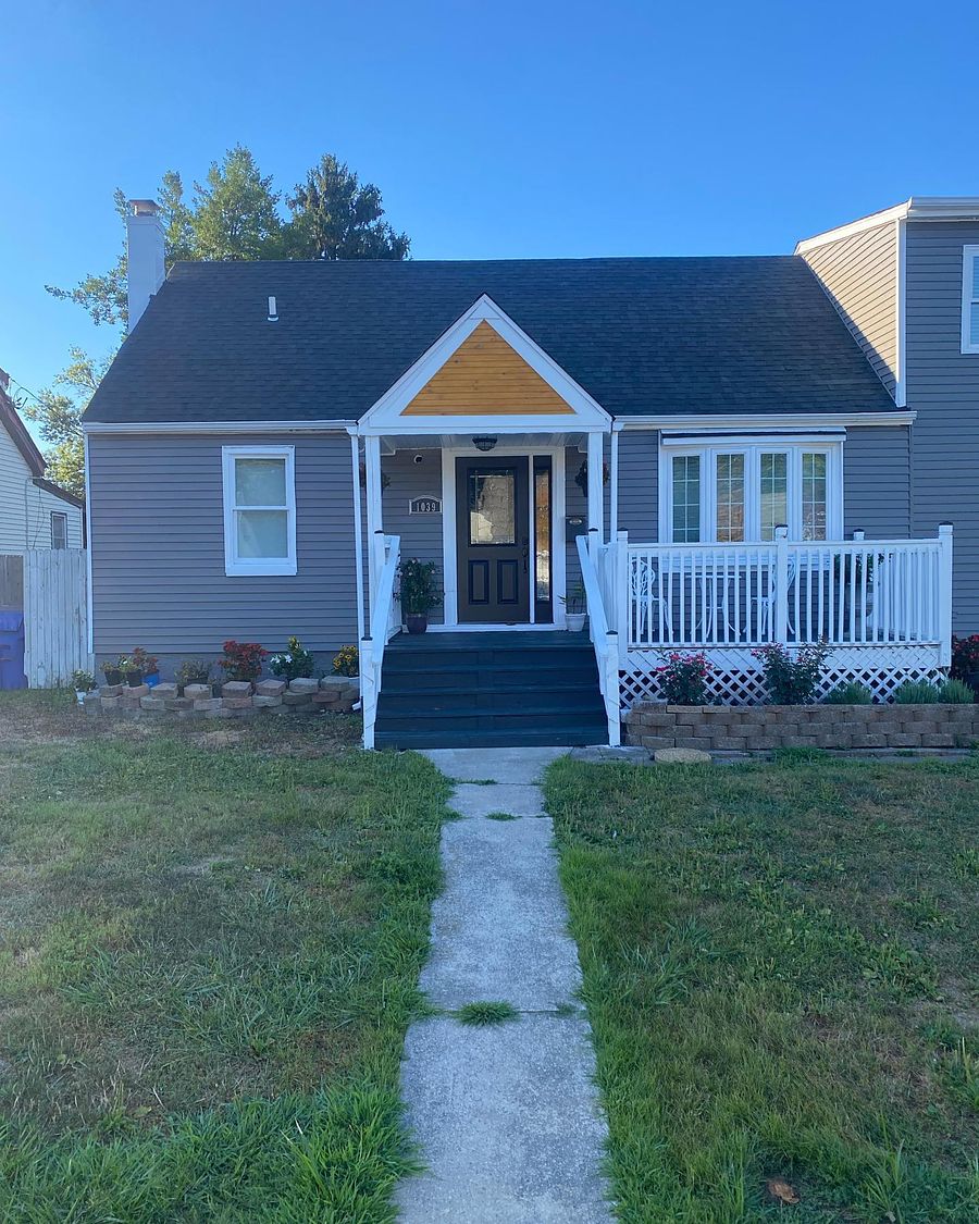 A cape with a new architectural shingle roof and grey siding, front elevation, by MG Roofing