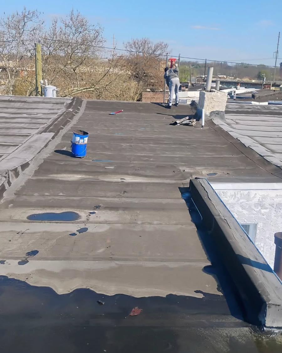 MG Roofing crew member working across a flat roof mid-repair