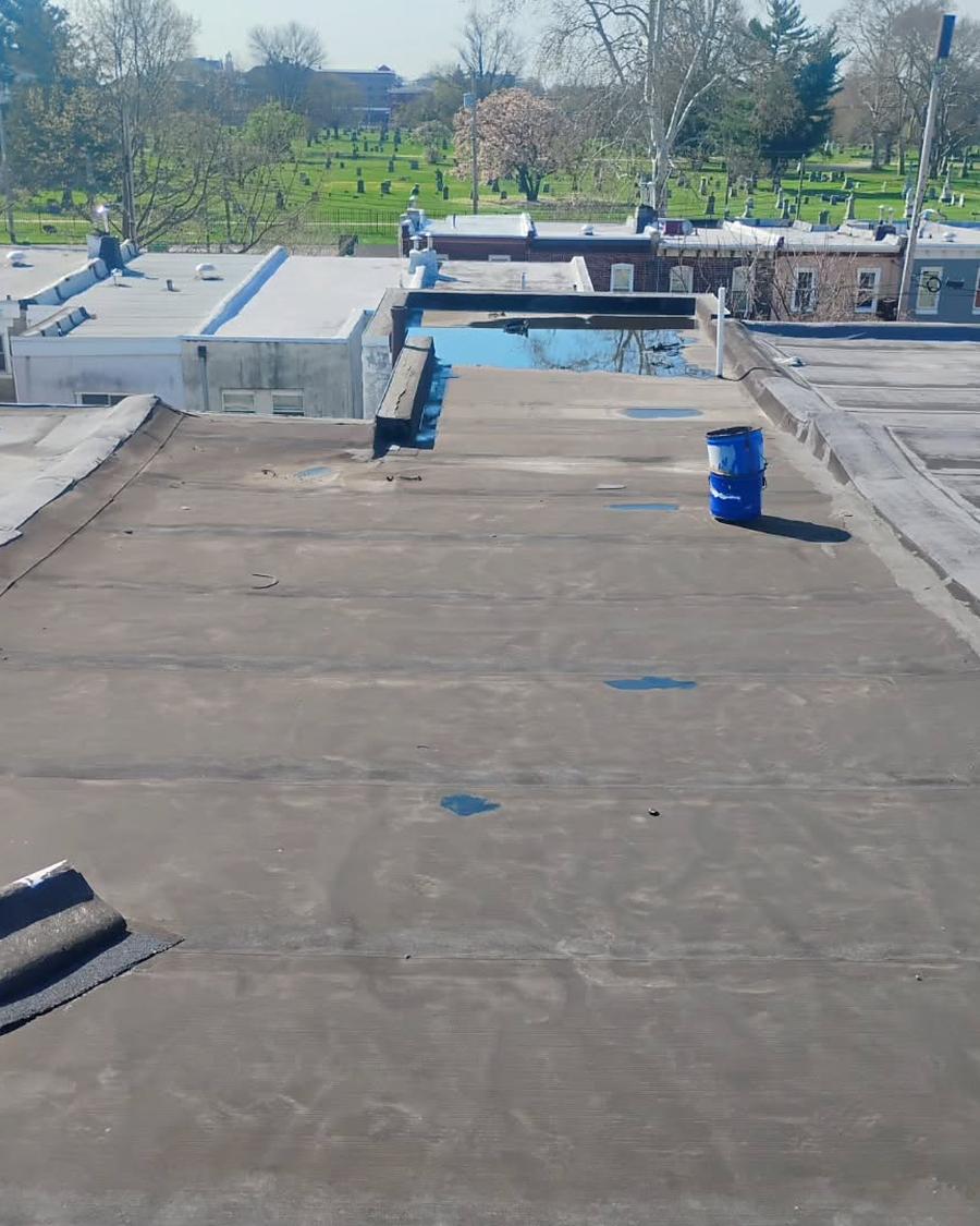 Grey, ponding flat roof before MG Roofing recoated it