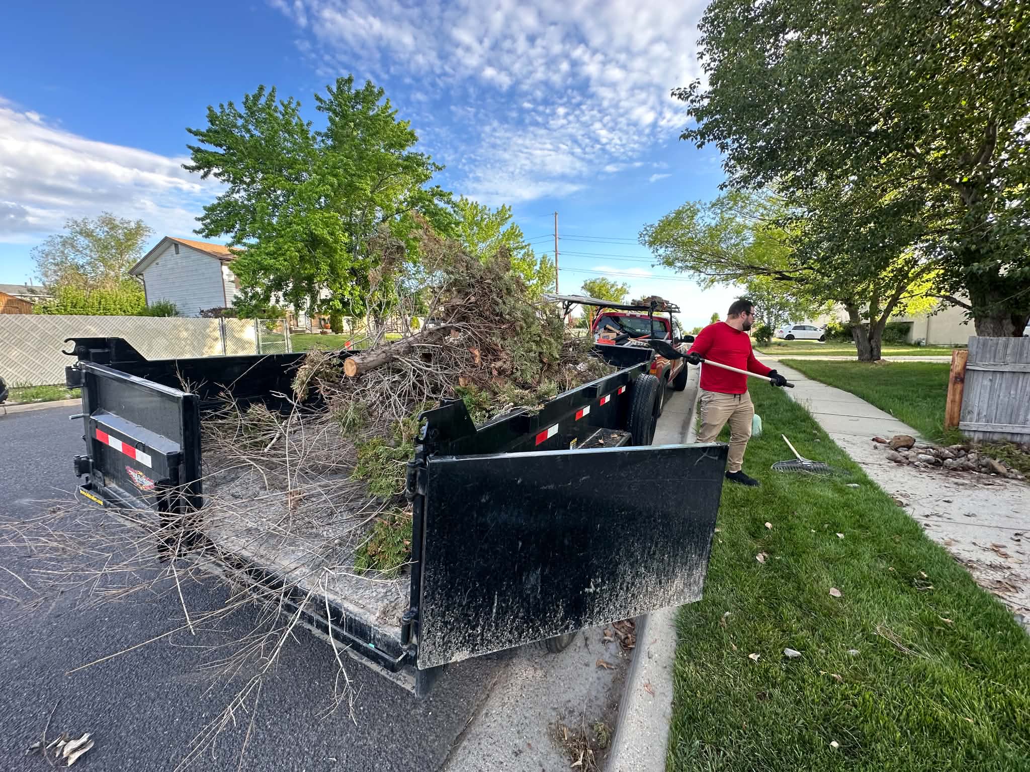 A crew member raking branches into a dump truck