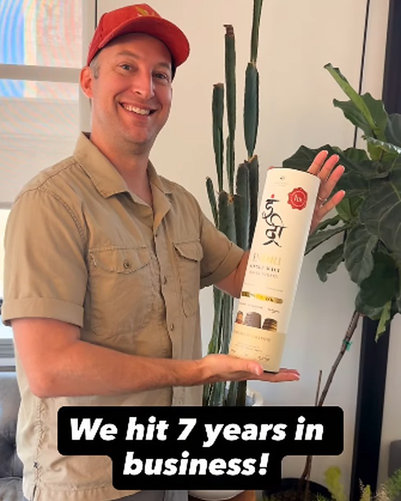RJ holding a bottle of whisky — “We hit 7 years in business!”