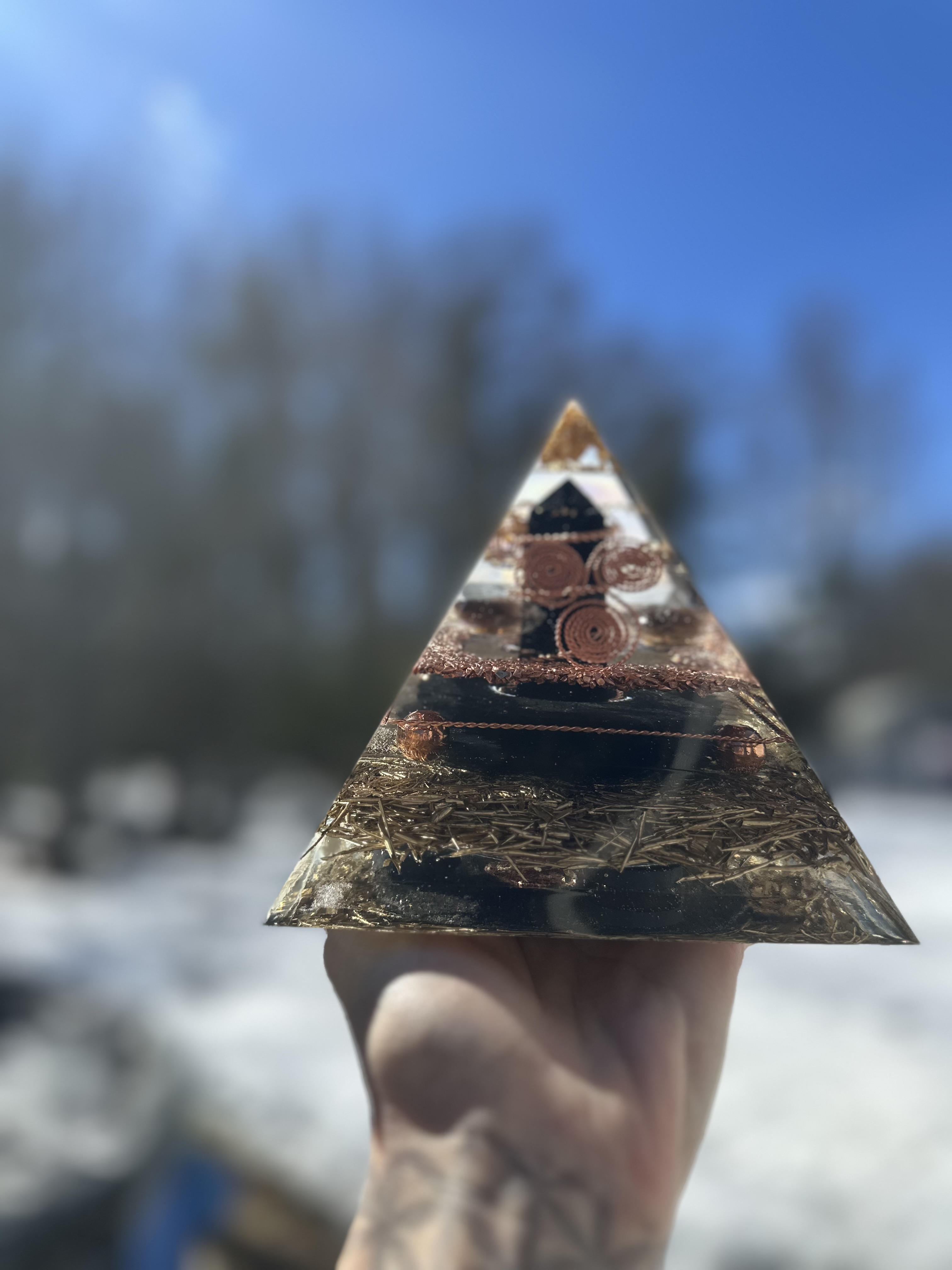 Large orgonite pyramid held in sunlight showing crystal clarity