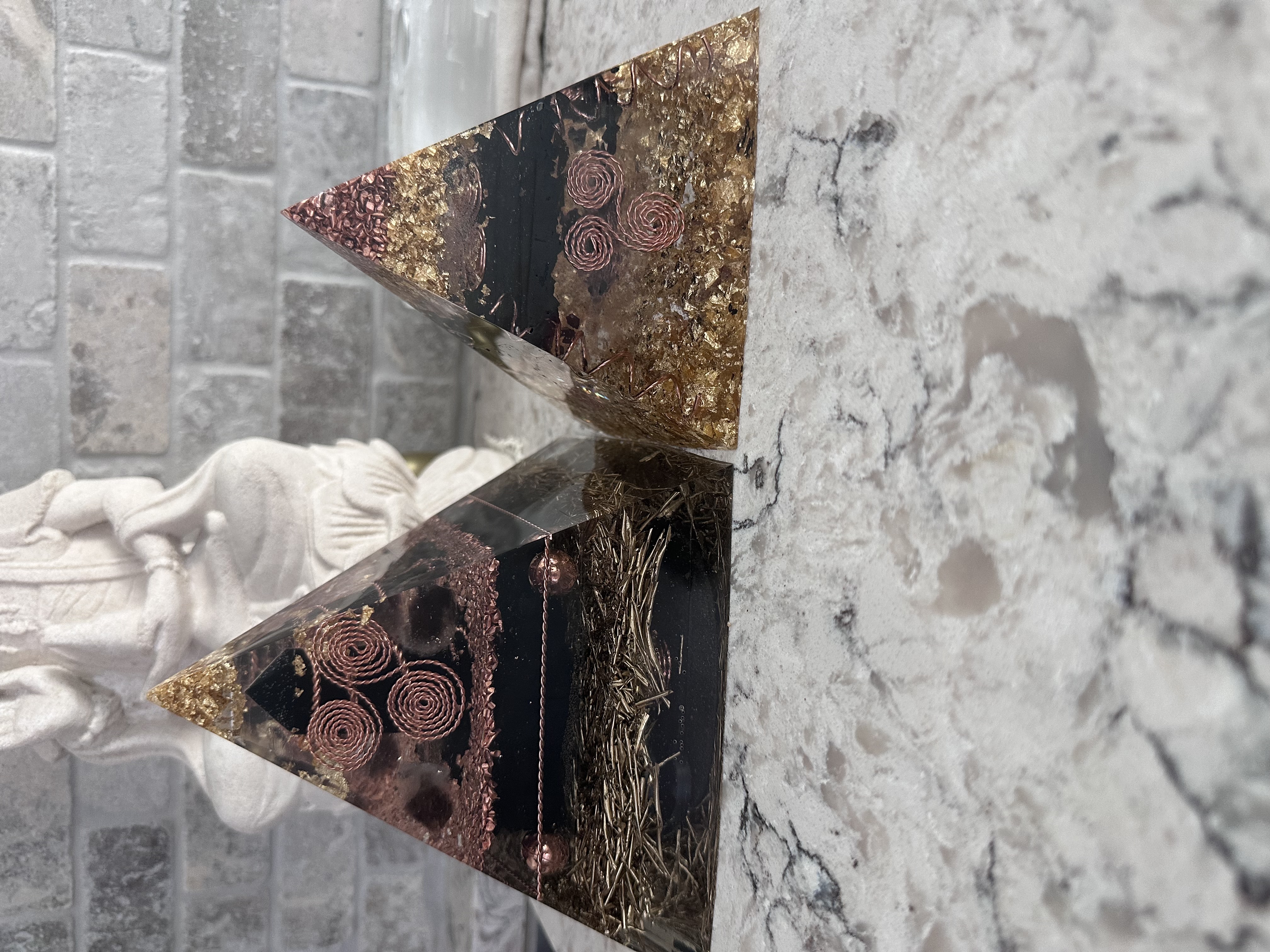 Both orgonite pyramids side by side on marble surface with Buddha statue, showing size comparison