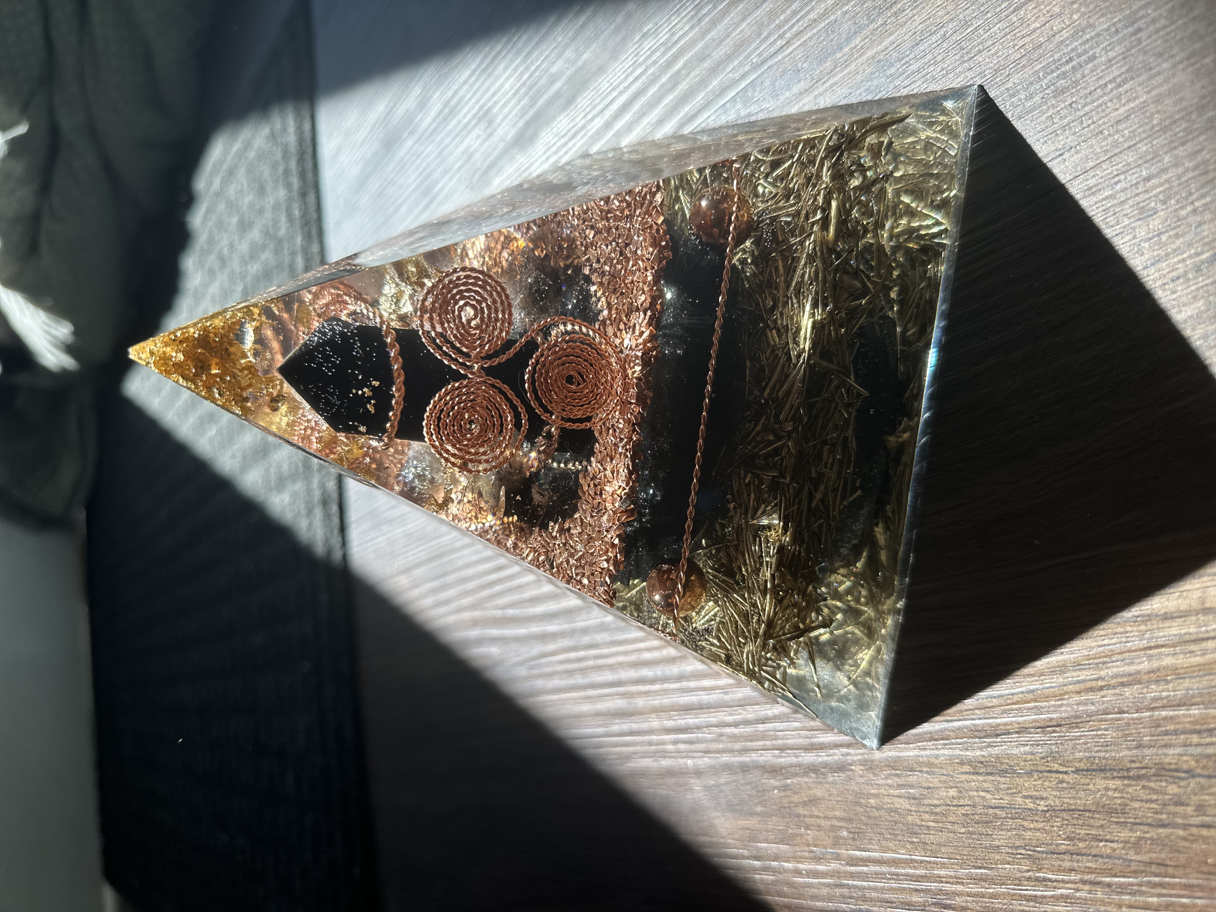 Handmade large orgonite pyramid with clear quartz and mixed metals on wood table, crafted by The Northern Daisy in Maine