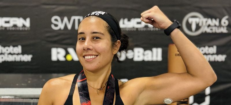 Dr. Elaina Rosario flexing after a race, wearing a finisher medal and a glucose monitor on her arm