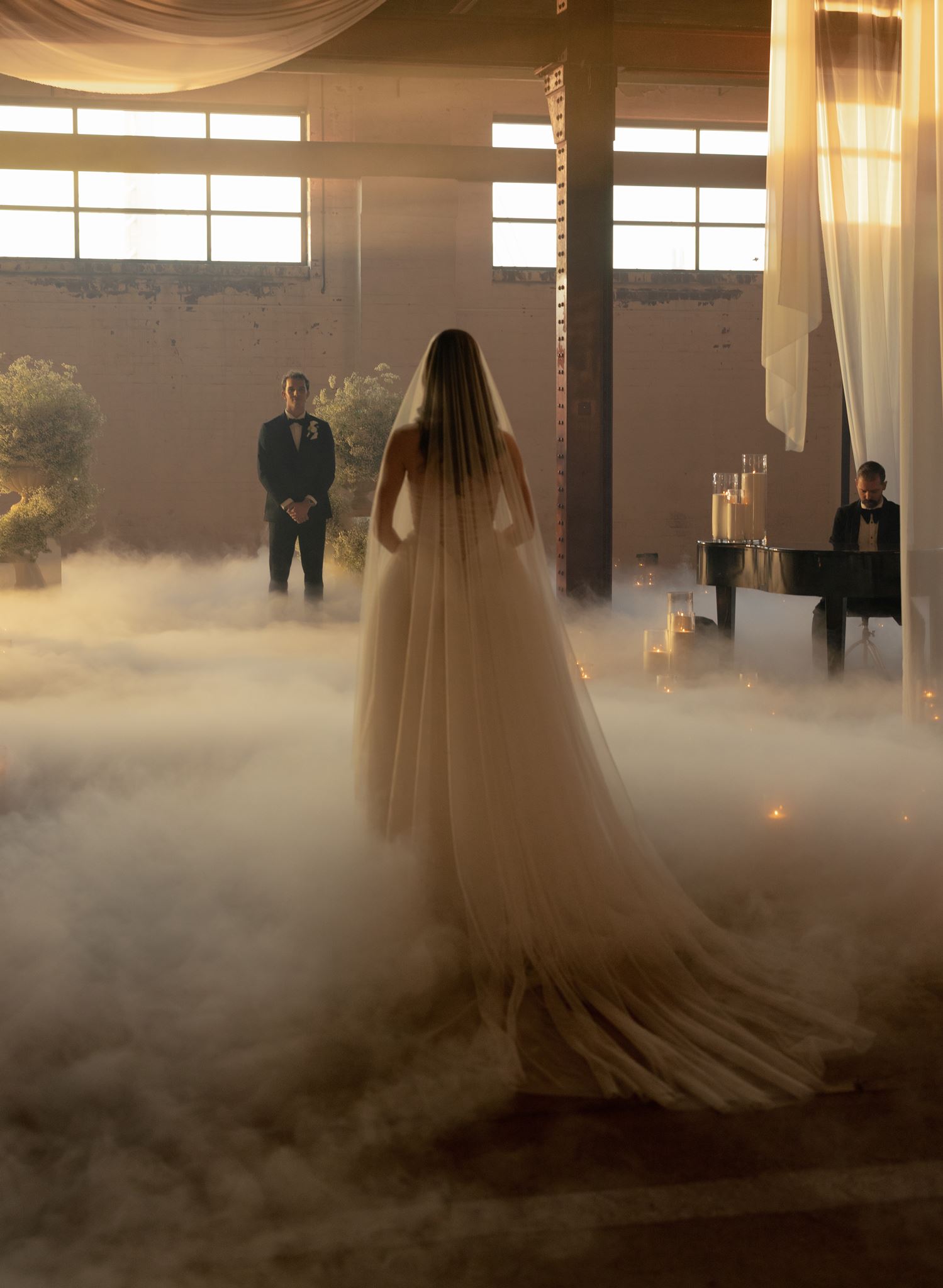 Bride walking through editorial candlelit installation aisle with sand candles and fog.