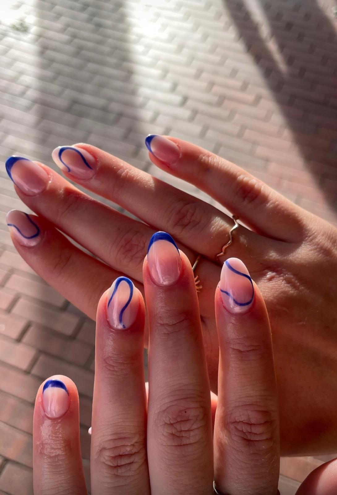 Close-up van gellak nailart met blauwe swirl-lijnen