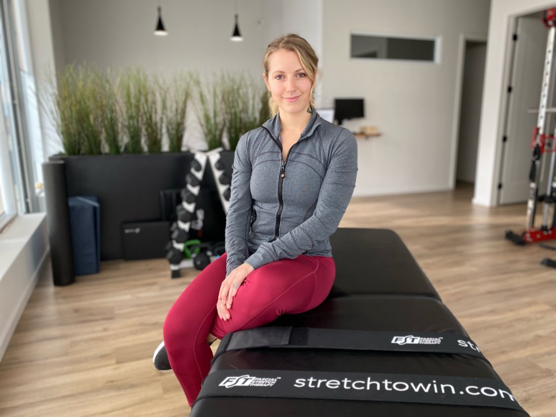 Victoria seated on the fascial stretch therapy table in her studio
