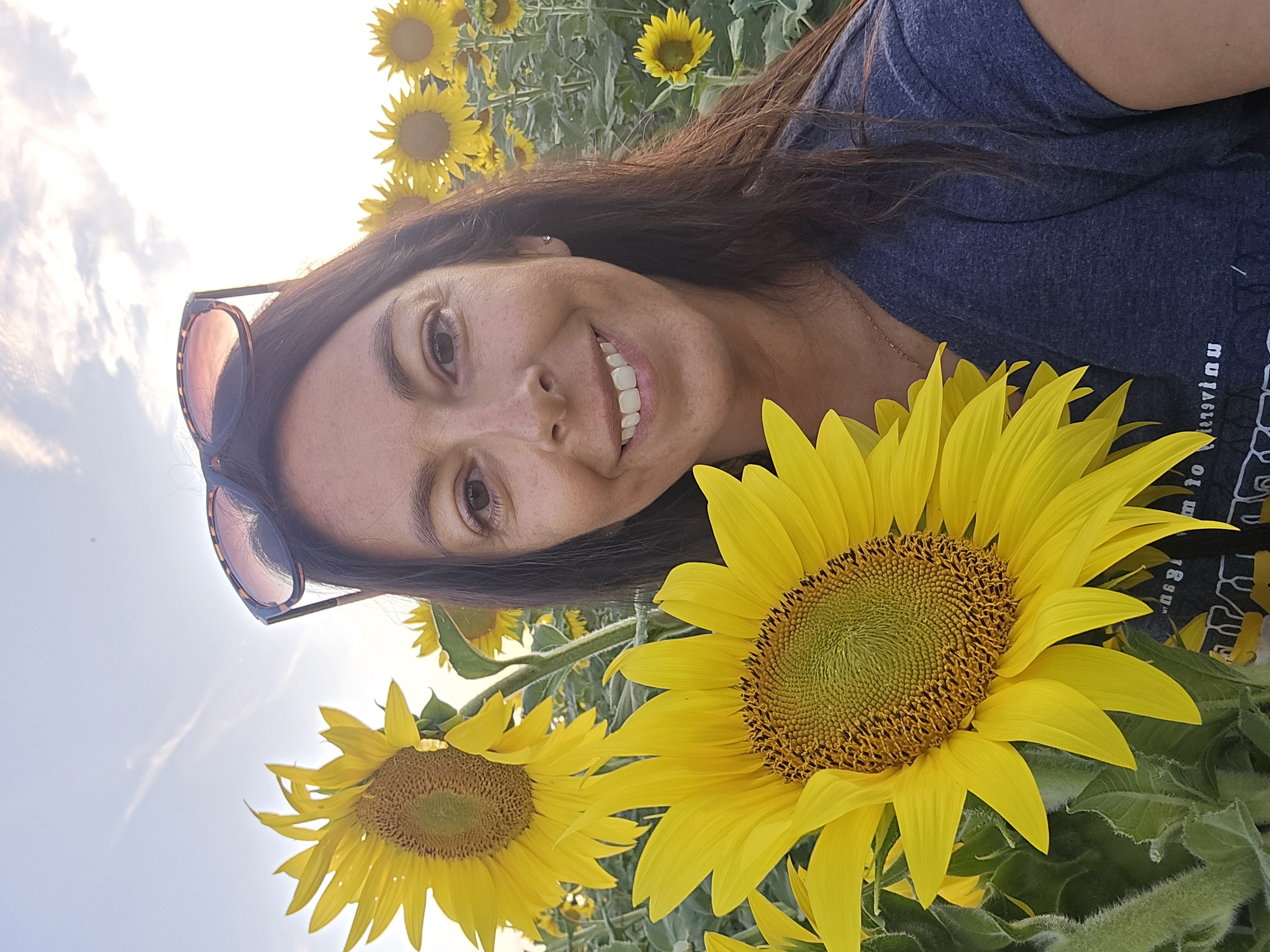 Lauren smiling in a field of sunflowers , thinking of get set program