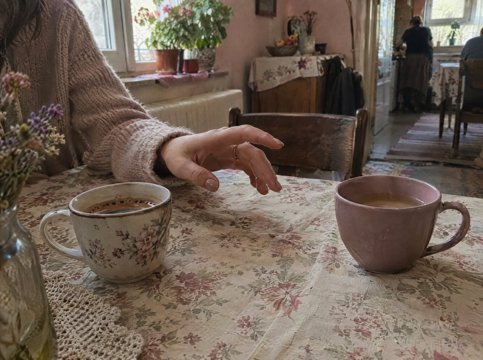 Două căni de ceai pe o masă cu față de masă înflorată