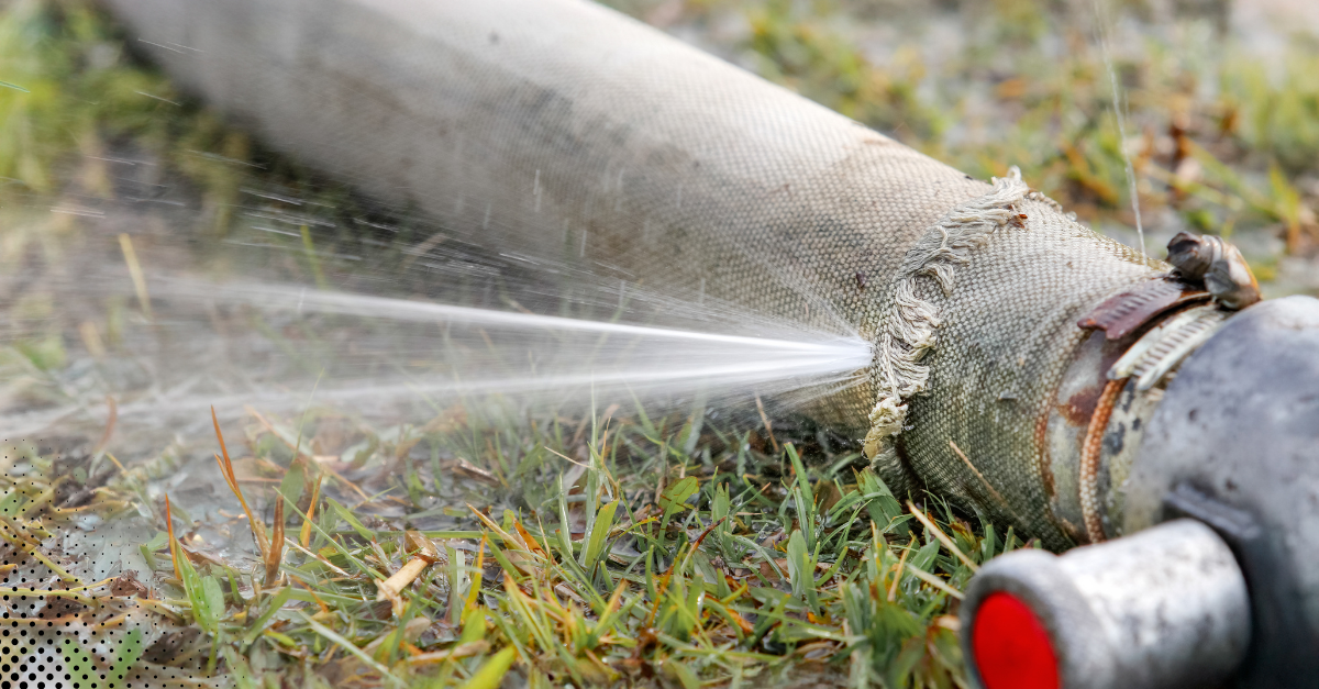 Leaking outdoor hose spraying water onto grass