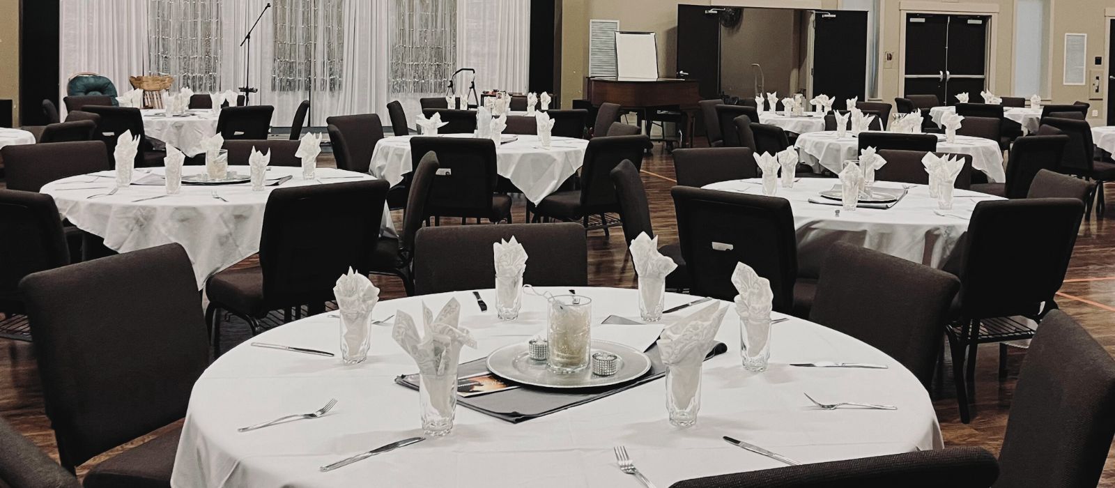 Elegant hosted gathering with round tables, white linens, twinkling centerpiece vases, and small rhinestone votive candle holders by Signature Experience Events 