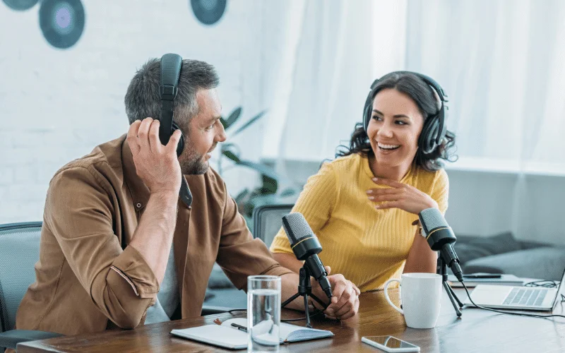 Two hosts recording a podcast episode together in a studio