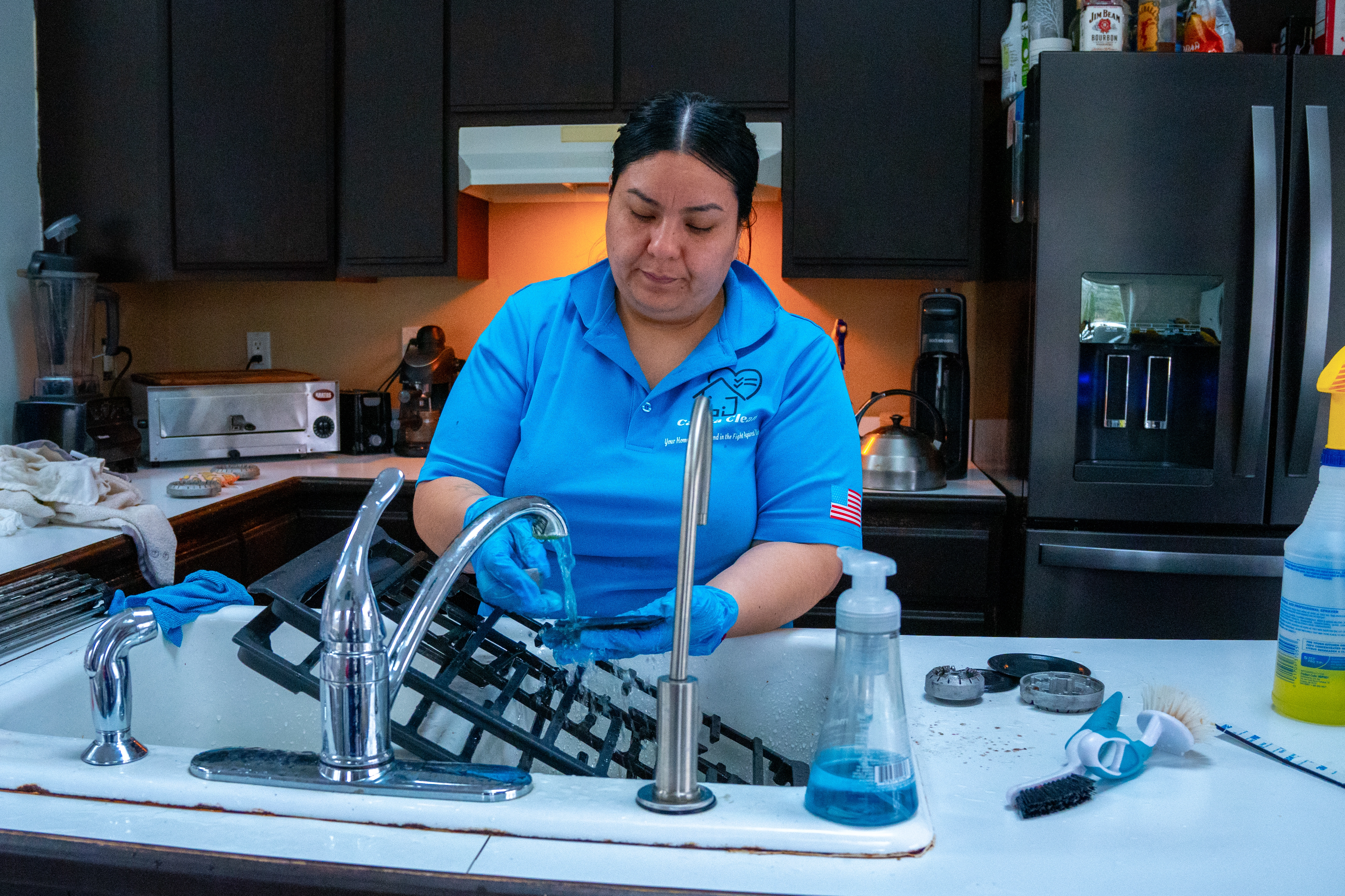 Casita Clean team member scrubbing stove racks during a deep clean in a suburban kitchen