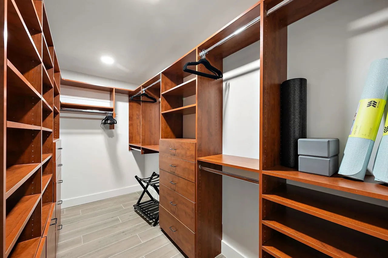 Walk-in closet with built-in wood shelving and hanging space, built by Logan Construction