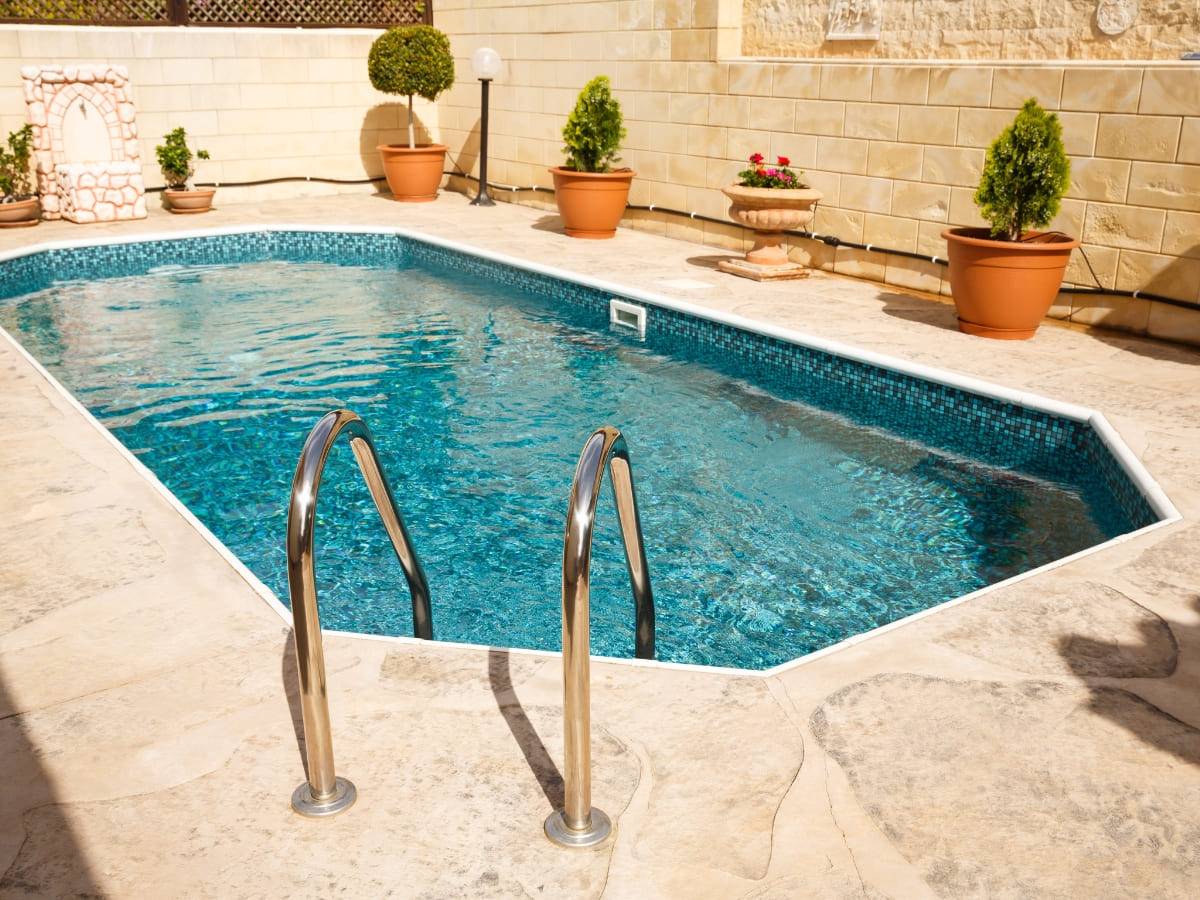 Clean outdoor pool with tiled walls and potted plants in Baldwin.