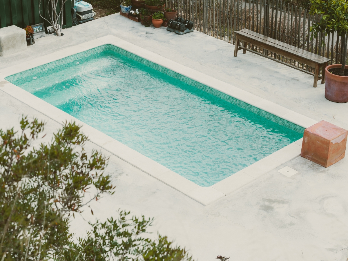 Stylish outdoor pool area with a pergola and stone wall, providing a luxurious and shaded relaxation spot.