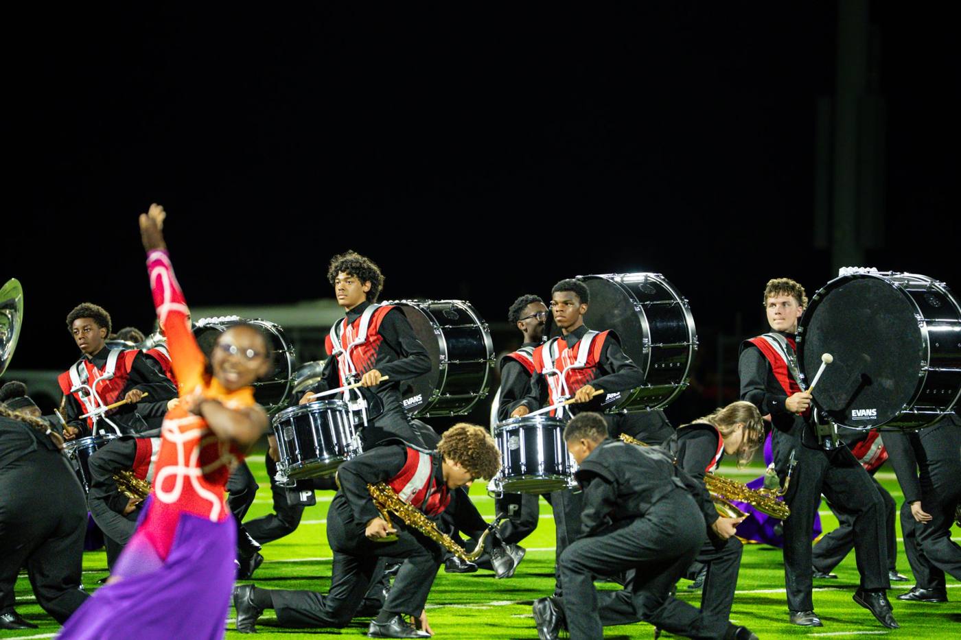 Del City drumline and saxophones kneel mid-show under the stadium lights