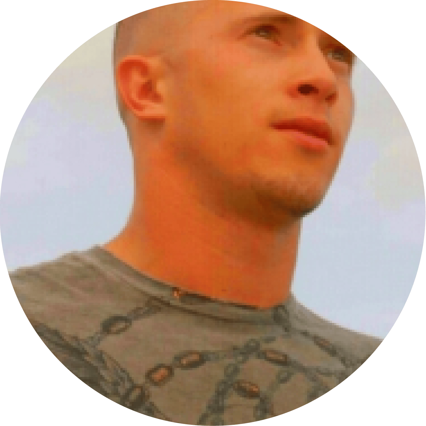 Circular portrait of a young man with a buzz cut looking upward against a pale sky.