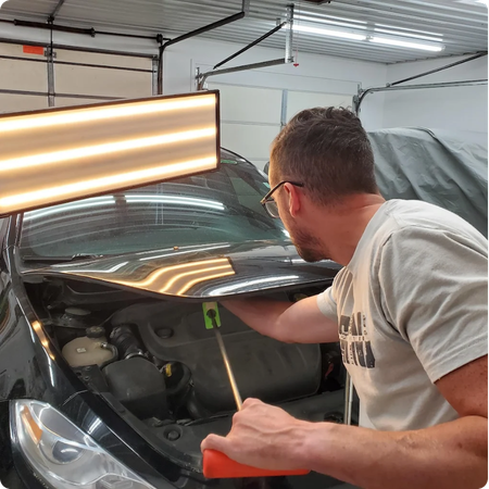 Paintless Dent Repair Technician Restoring Vehicle Panel