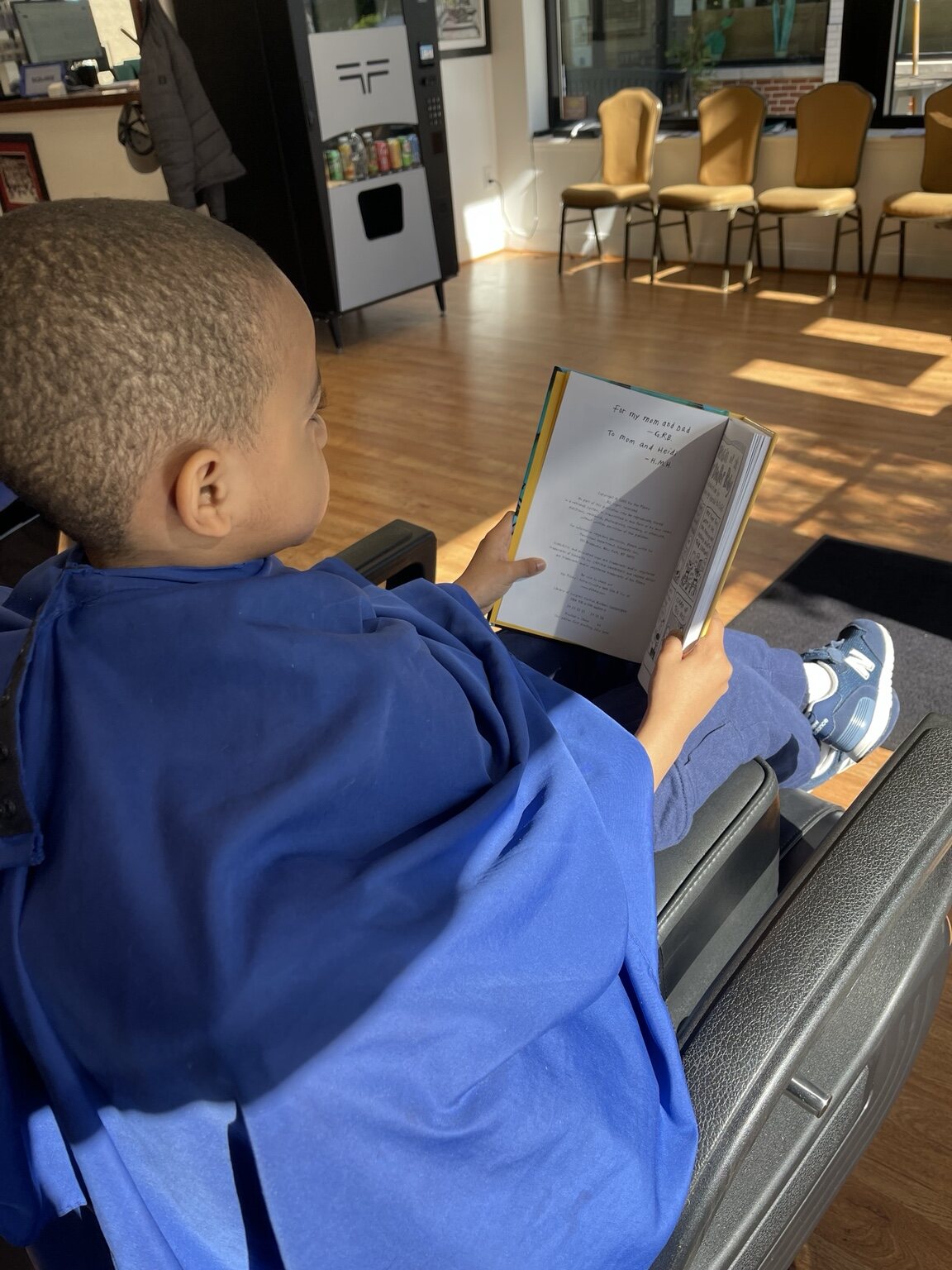 Child reading comfortably during a haircut appointment at The Ultimate Barber in Alexandria