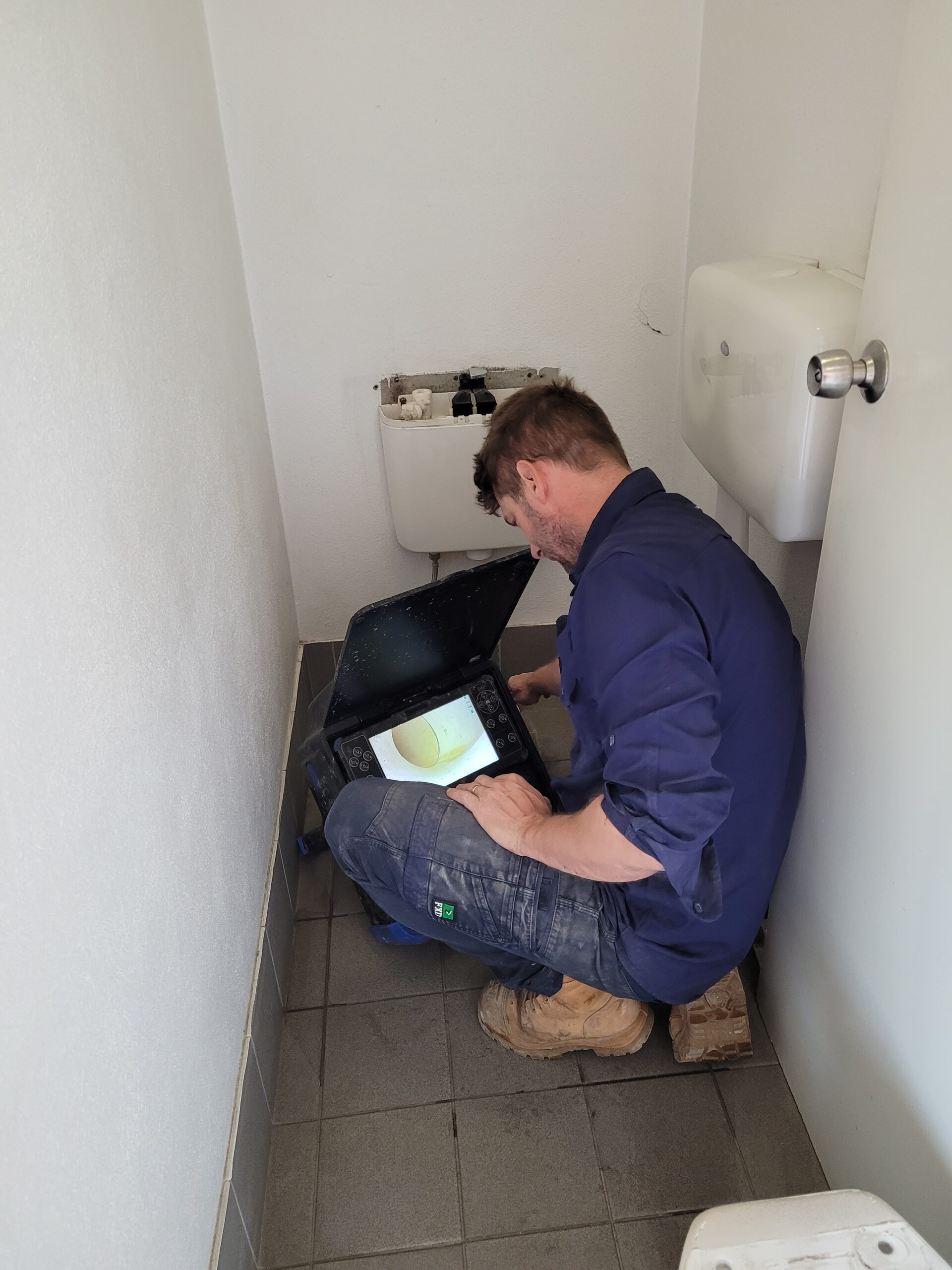 Plumber performing CCTV drain inspection on a blocked drain at a Brisbane home