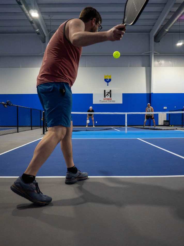 Doubles pickleball rally on indoor courts at Pickleball Kingdom Pflugerville