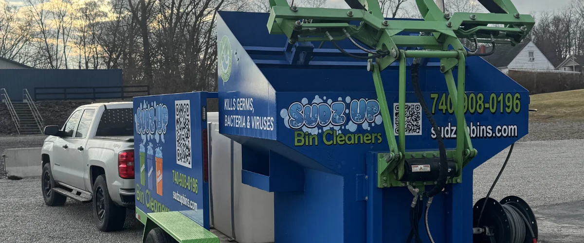 A bright blue and green Sudz-Up Bin Cleaners trailer with a QR code and contact info, featuring bin cleaning services. A bright blue and green Sudz-Up Bin Cleaners trailer with a QR code and contact info, featuring bin cleaning services.
