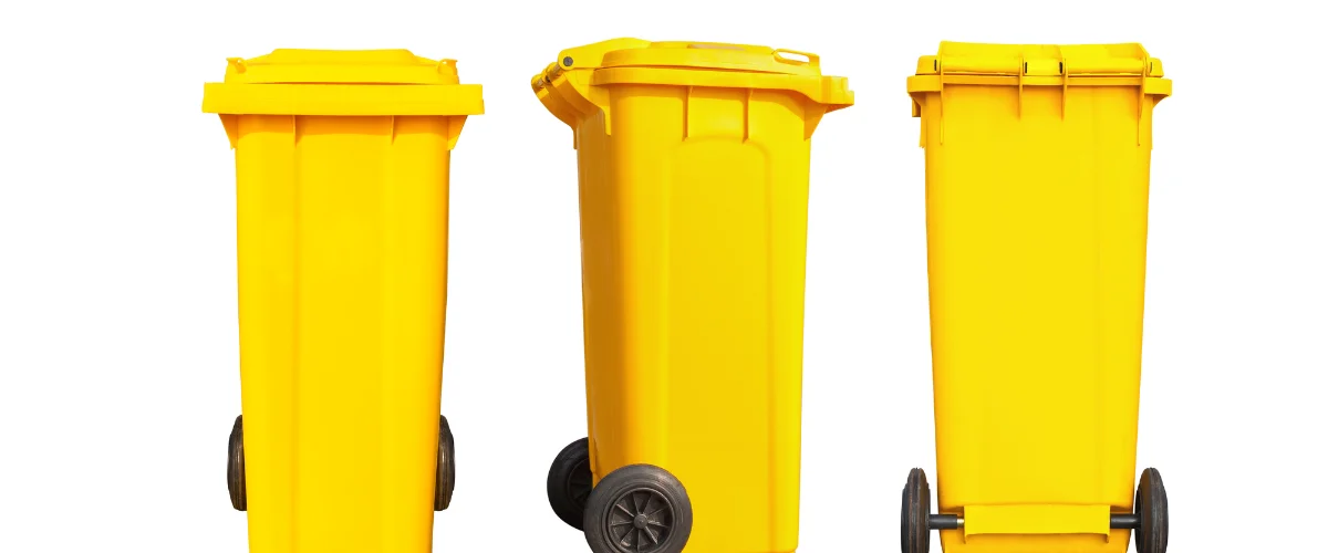 Three bright yellow plastic waste or recycling bins with black wheels, shown in various angles against a white background. Three bright yellow plastic waste or recycling bins with black wheels, shown in various angles against a white background.